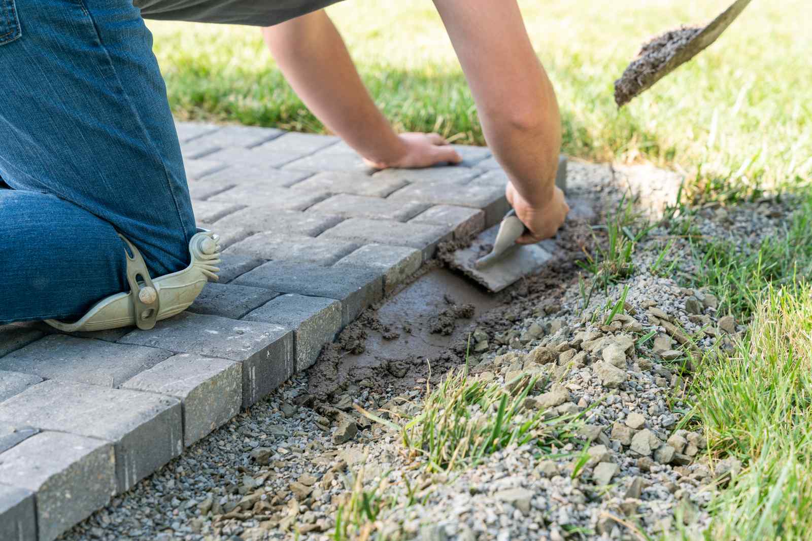 Worker Putting Cement to Prevent Paver Shifting and Maintain a Level Surface