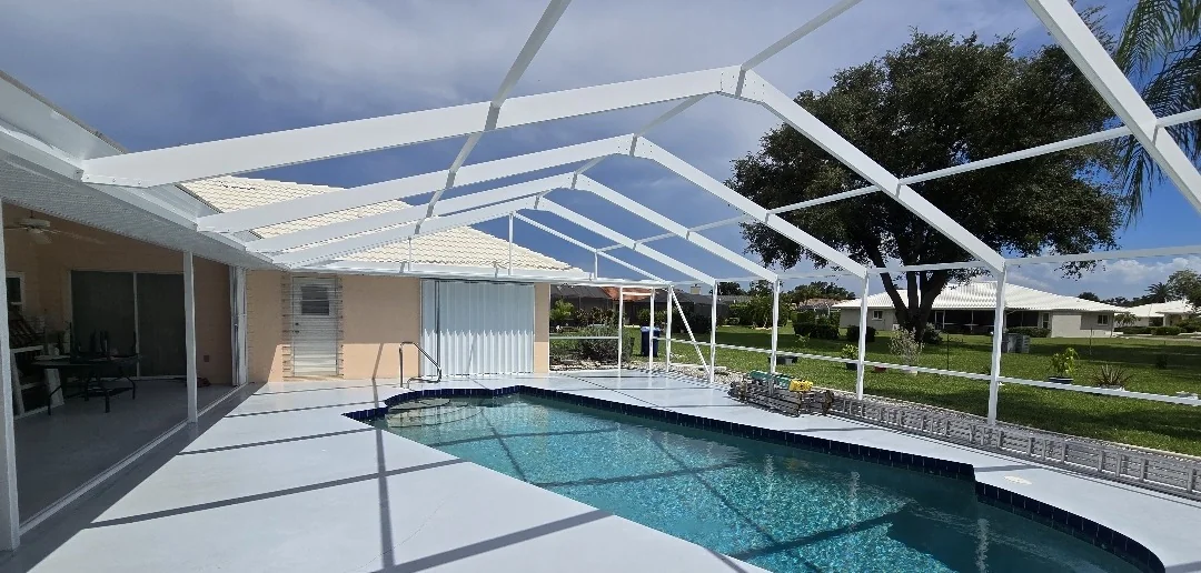 Pool cage stripped to the bare aluminum frame over the pool during a restoration in Venice, before repainting and rescreening