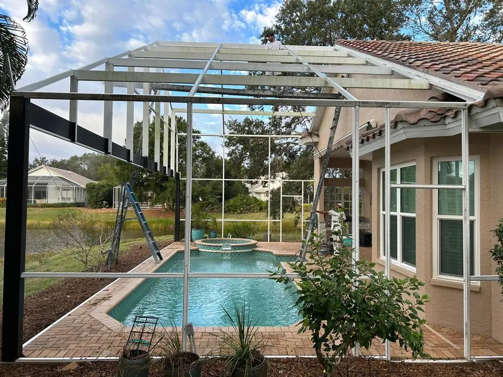 Aluminum pool cage frame under construction over a pool before the screen is installed