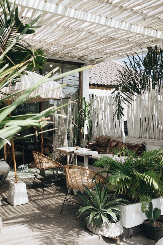 white table with brown wicker chair beside plants making the perfect outdoor space